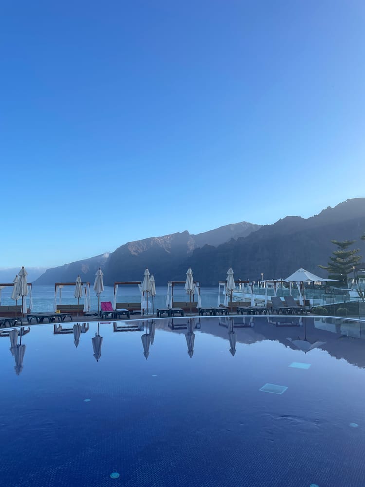 An early-morning view of high cliffs and a blue hotel pool